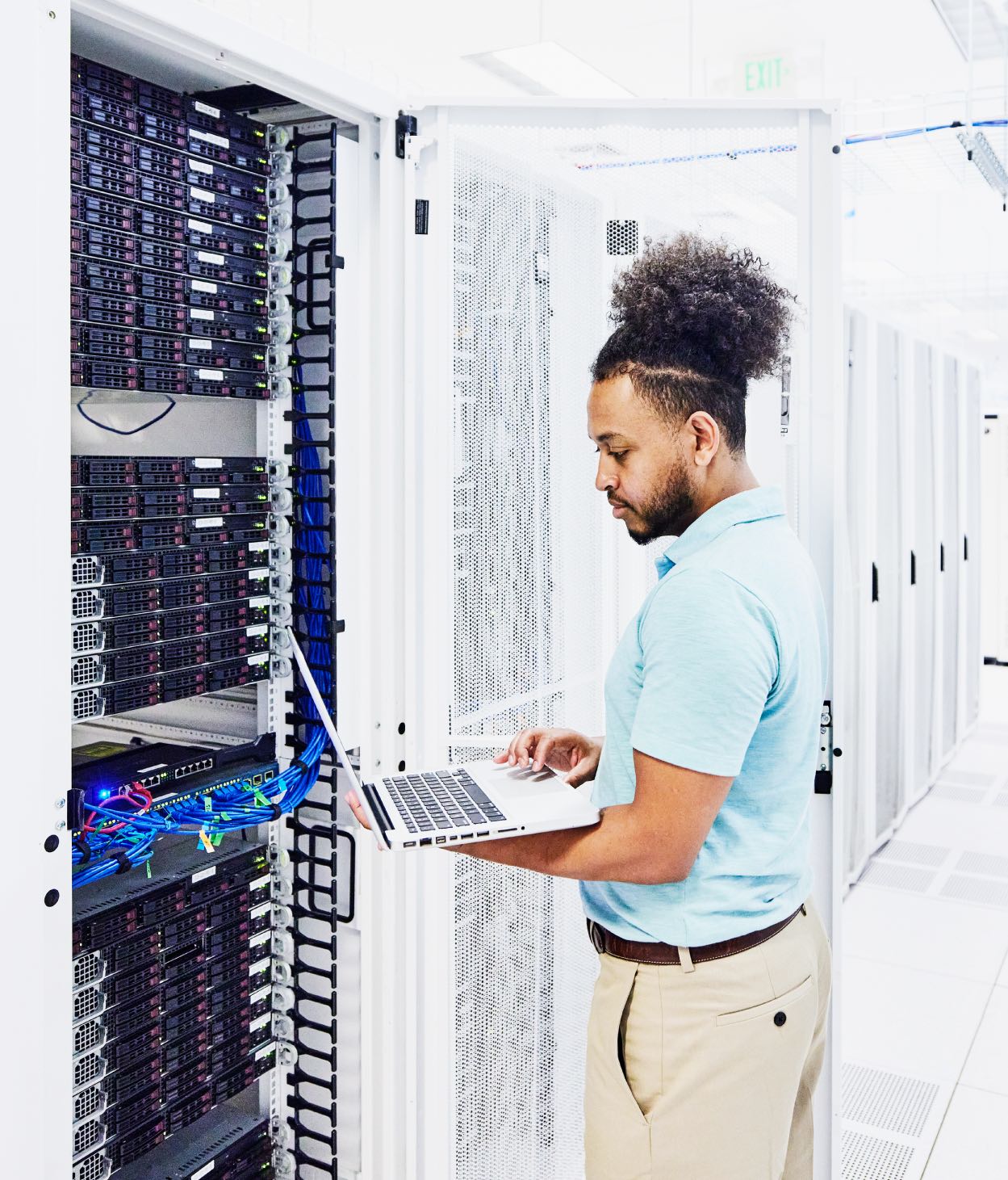 IT employee diagnoses server software in a server room.